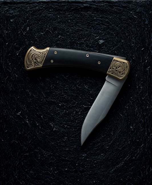 Hand engraved buck 110 folding knife. The engraving features scrollwork. The knife is resting on a dark textured background