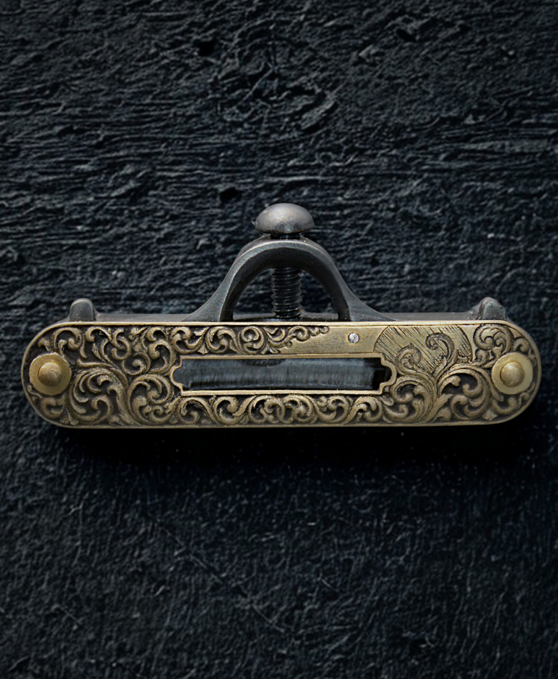Hand engraved gold tone vintage leveler, sitting on a black textured background.