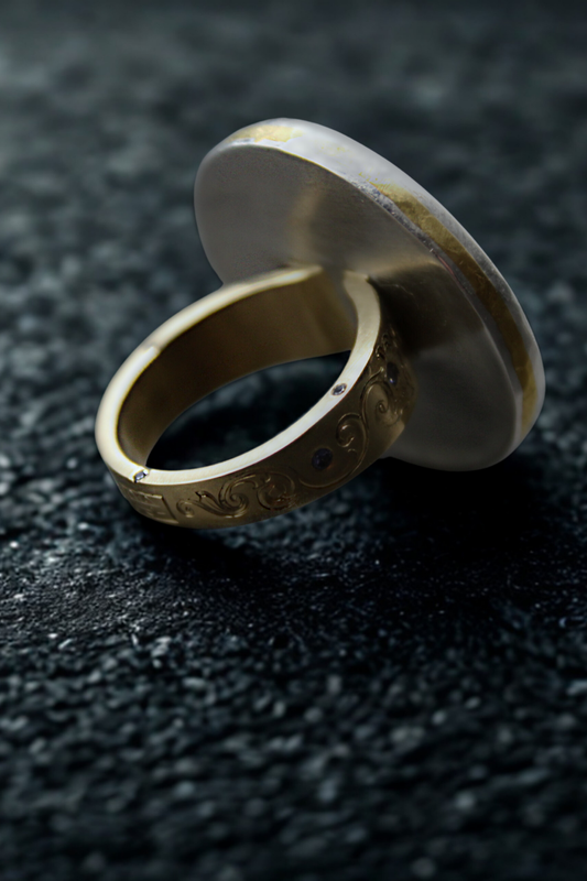 Gold ring with engraved design on a dark textured surface