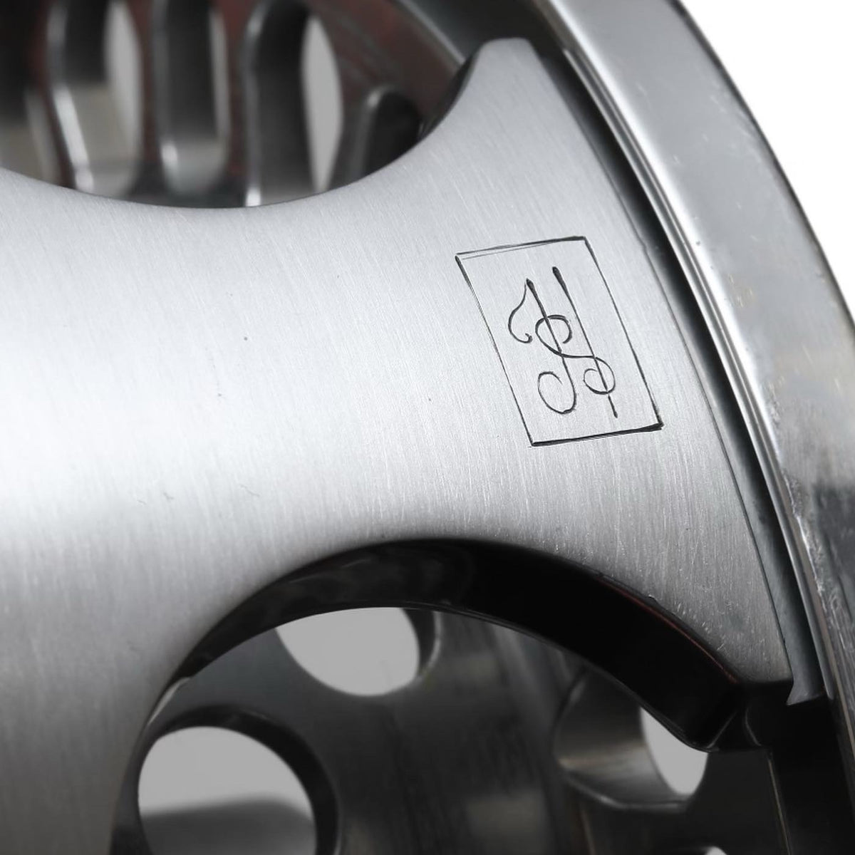 Close-up of a metallic rim with a logo on a white background