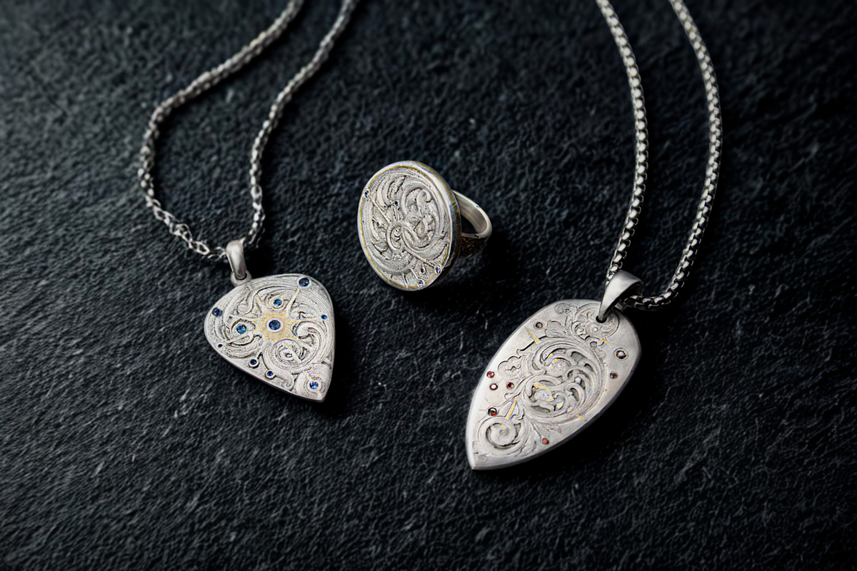Silver jewelry set with pendants and a ring on a dark surface