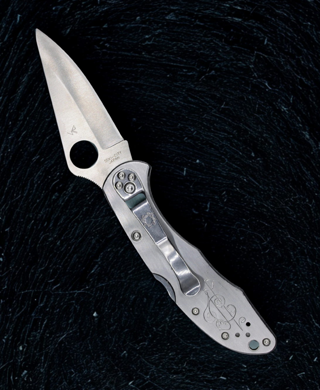 Silver folding knife on a black textured background