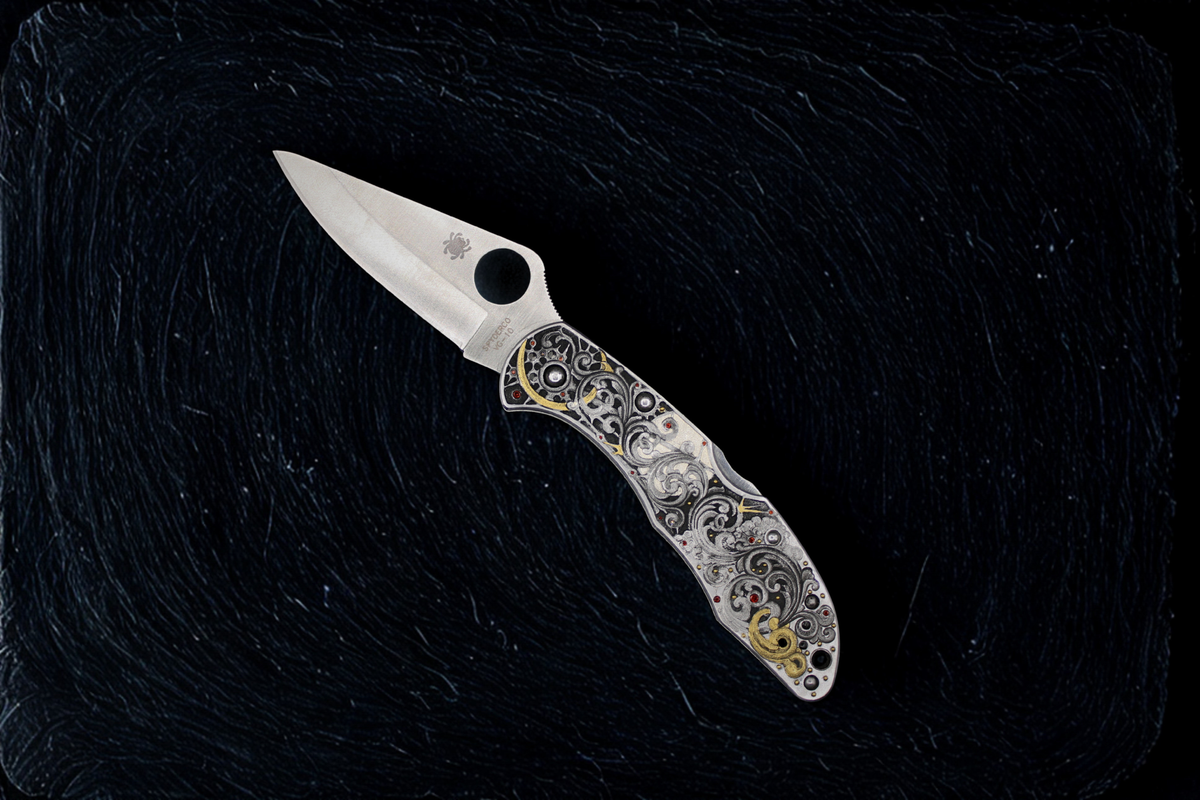 Folding knife with decorative handle on a black textured background